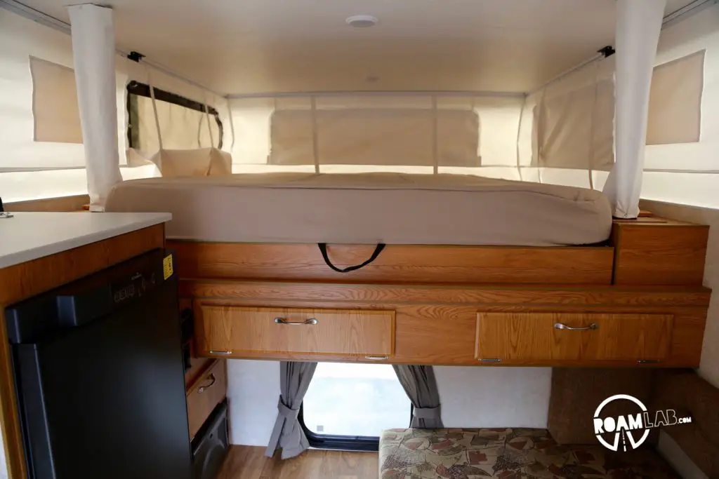 The lights are off inside this pop-up camper, but that doesn't mean it's dark. Midday sunshine still streams in through the light white fabric that covers the expanding portion of the pop-top.