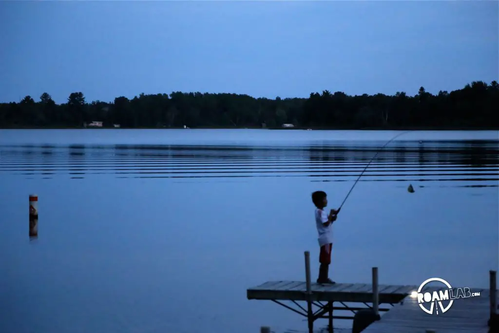 Children around the lake were reticent to stop fishing until it was so dark that they could no longer see their hooks.
