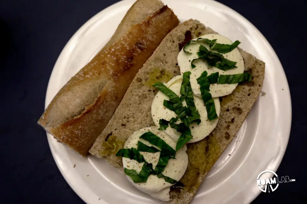 Fresh basil sprinkled over mozzarella. The making of a delicious Class in the Campground Prosciutto Mozzarella Sandwich.