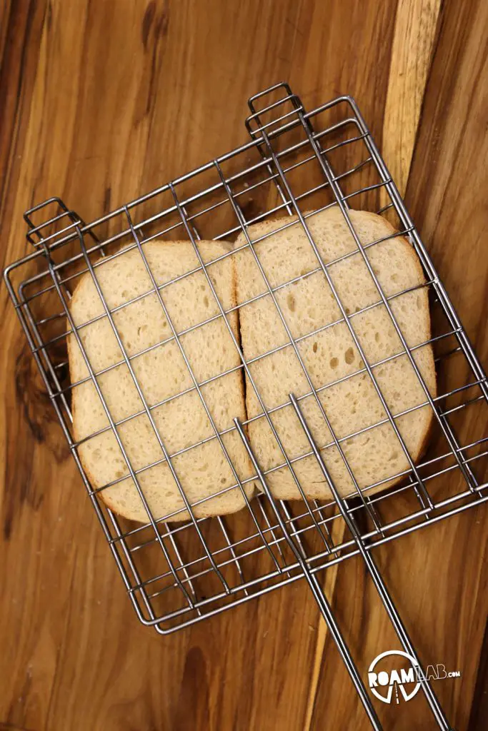 Placing the Glamper’s Bacon Brie Apricot Toasted Sandwich in a grill basket for toasting over the open fire.