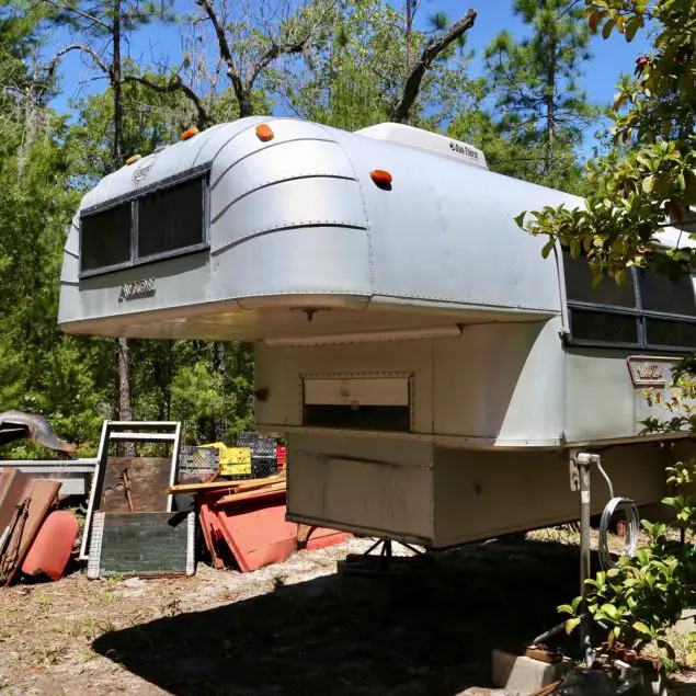 1970 Avion C11 truck camper floating on jacks in the back yard of its previous owner.