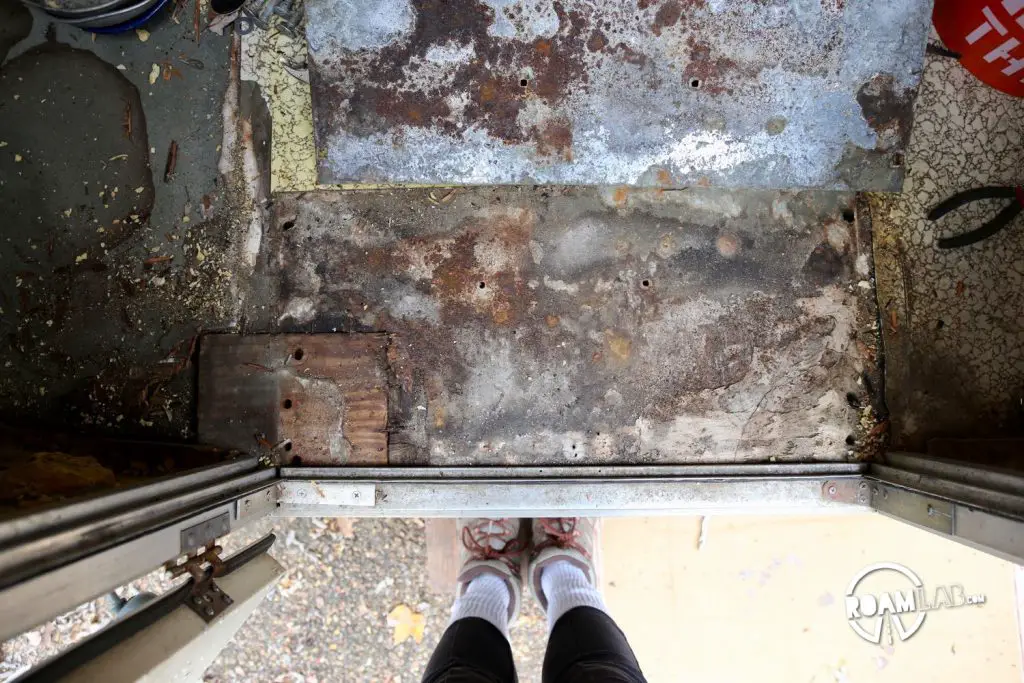 This section of the original entry shows previous efforts the patch and strengthen the rotting floor including the block of wood on the lower left and some kind of hardened putty material on the lower right.
