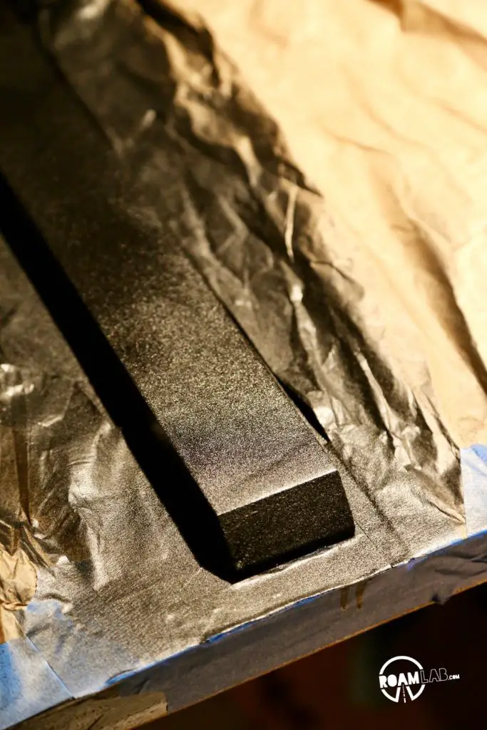 Spraying gritty bed-liner onto the truck camper floor rails.