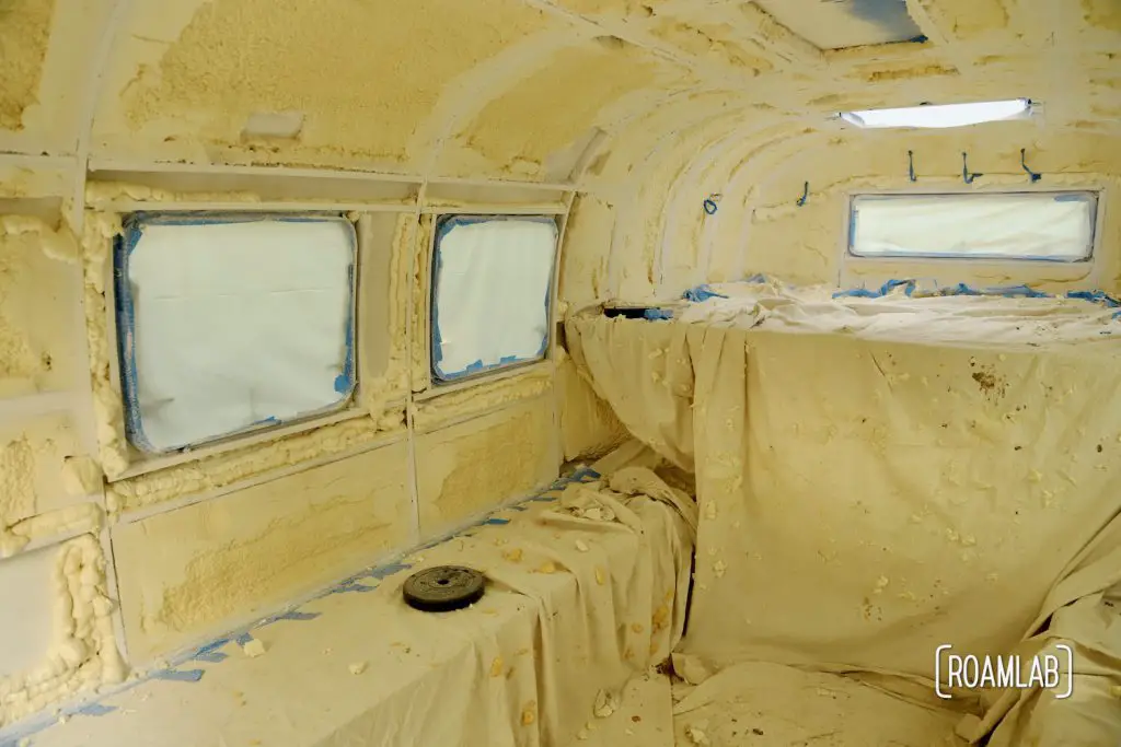 Truck camper interior covered with drop clothes, plastic sheet, and masking tape after painting.