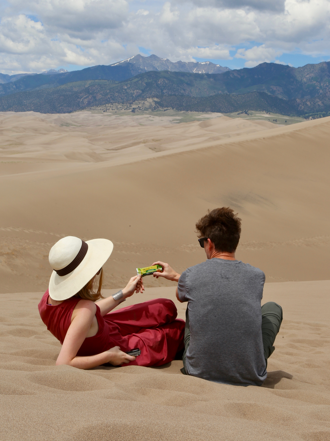 Woman and man sharing a granola bar in Great Sand Dunes National Park