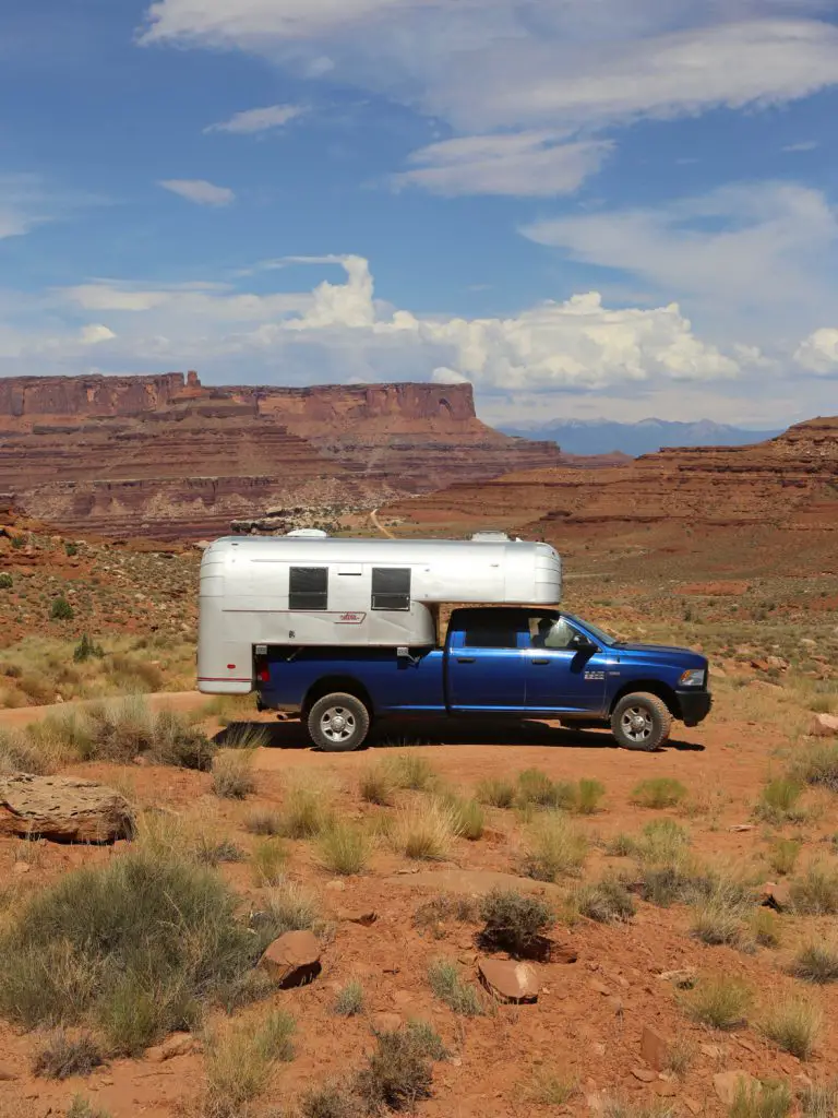Aluminum truck camper on a blue truck on a dirt road in the middle of Canyonlands National Park