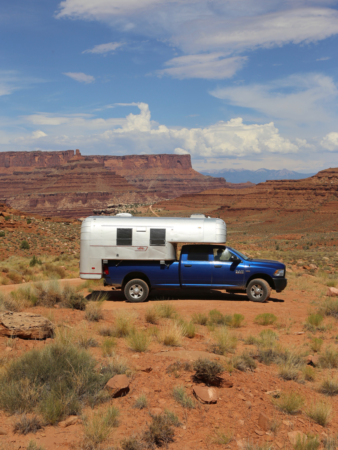Aluminum truck camper on a blue truck on a dirt road in the middle of Canyonlands National Park