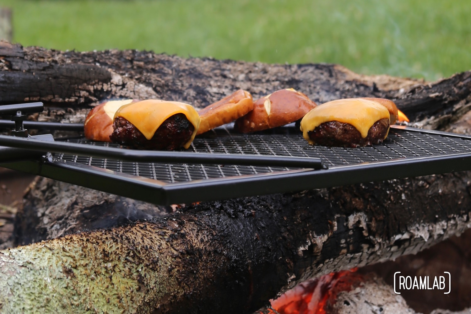 Grilling burgers outside, over a campfire on the Adjust-A-Grill.