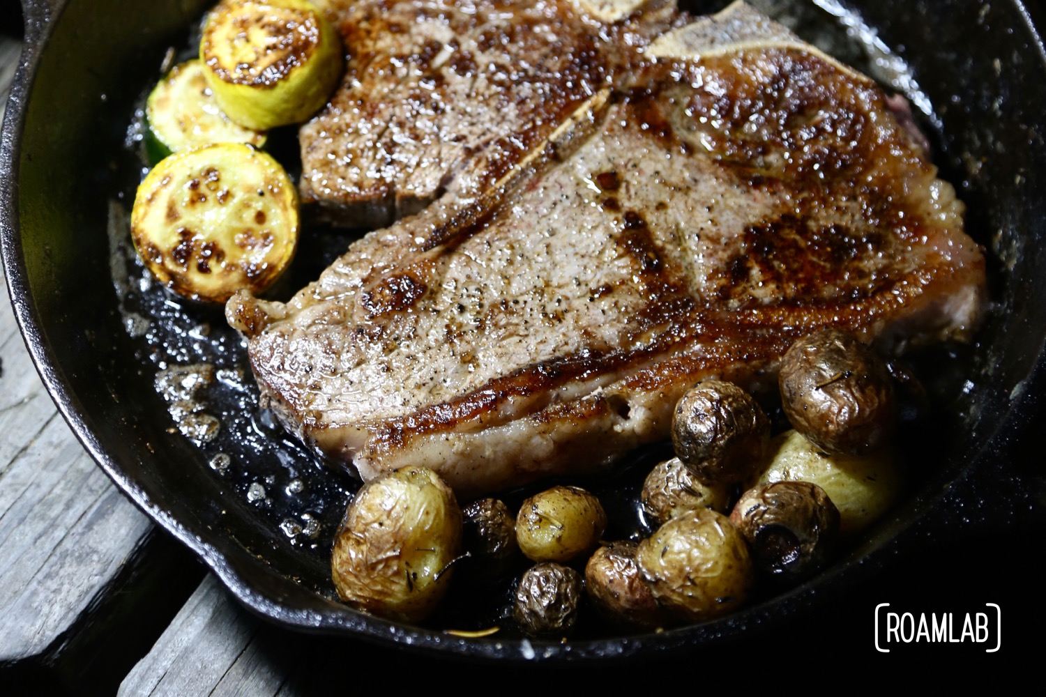 Porterhouse ready to eat with yellow squash and roasted potatoes.