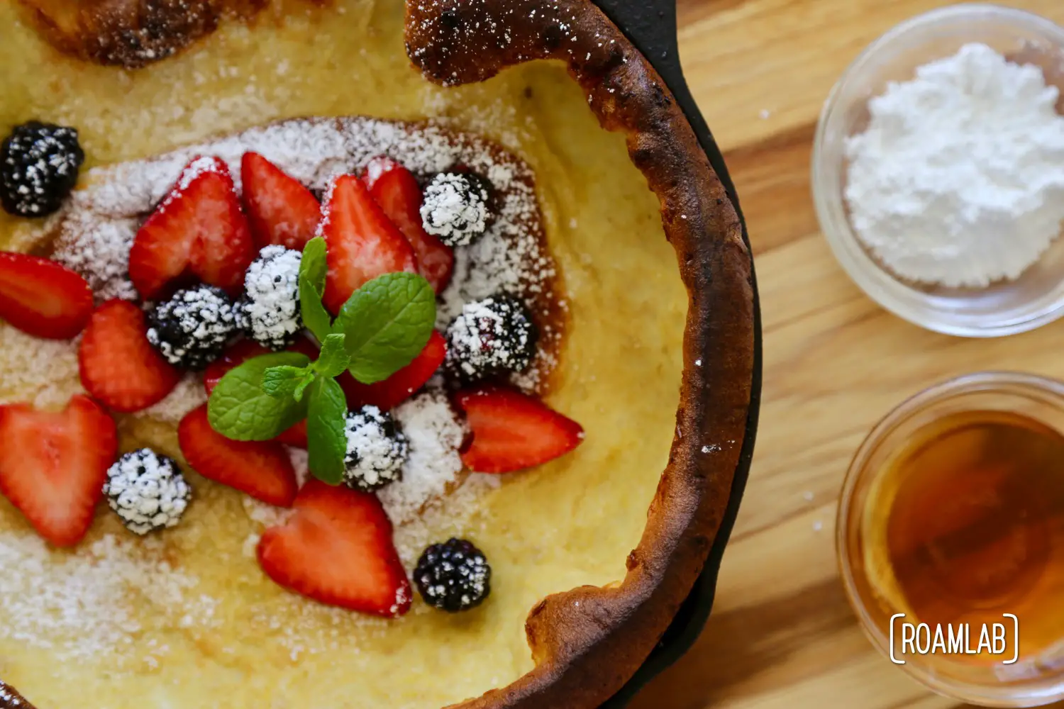 Blackberries, strawberries, powdered sugar and mint on a dutch baby pancake.