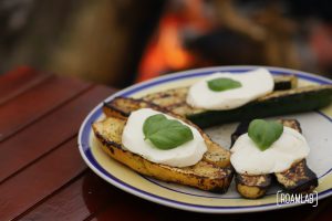 Grilled zucchini with a slice of mozzarella cheese and leaf of basil.