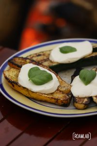 Grilled zucchini with a slice of mozzarella cheese and leaf of basil.