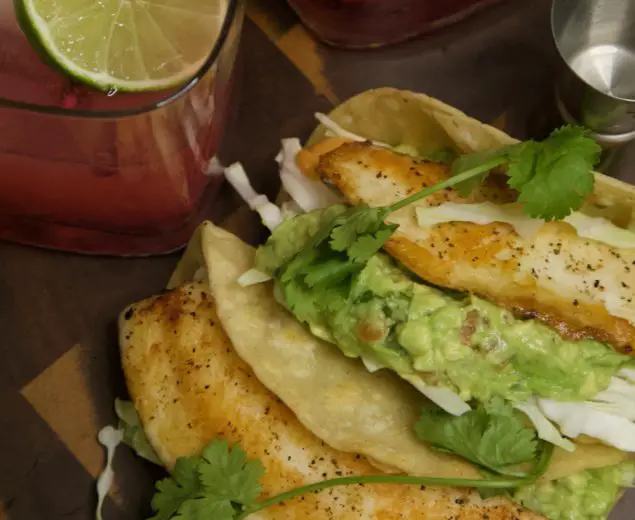 Tilapia fish tacos with guacamole and pomegranate margaritas.