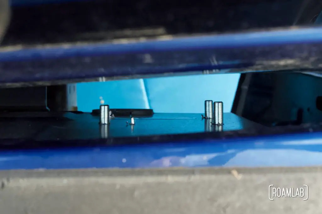 Four bolts sticking through guide plate inside the truck bed, ready to secure the front anchor mount.