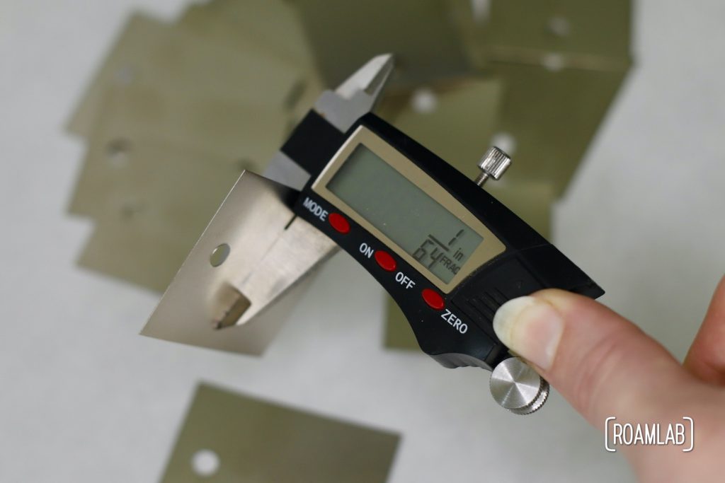 Using digital calipers to measure the thickenss of sheet metal bus bars. The display reads 1/64 inch.