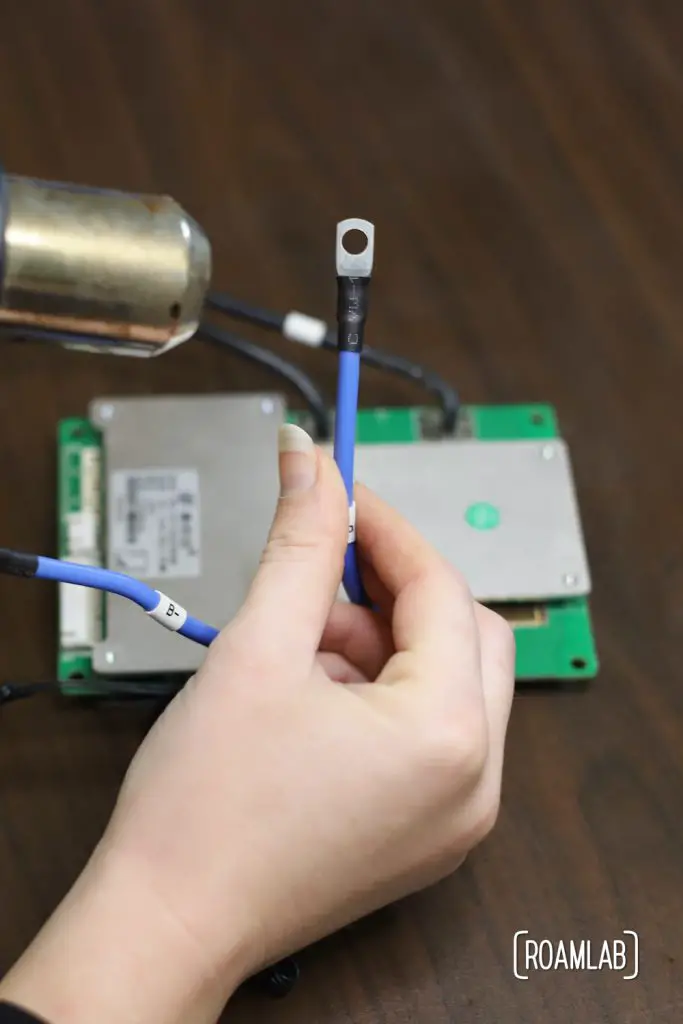 Using a heat gun to secure heat shrink around the transition from main BMS power wire and terminal.