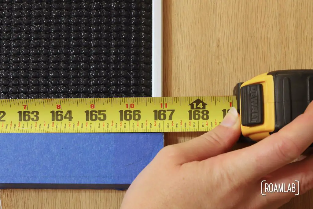 Measuring tape held up against a solar panel indicating a 167-inch distance.