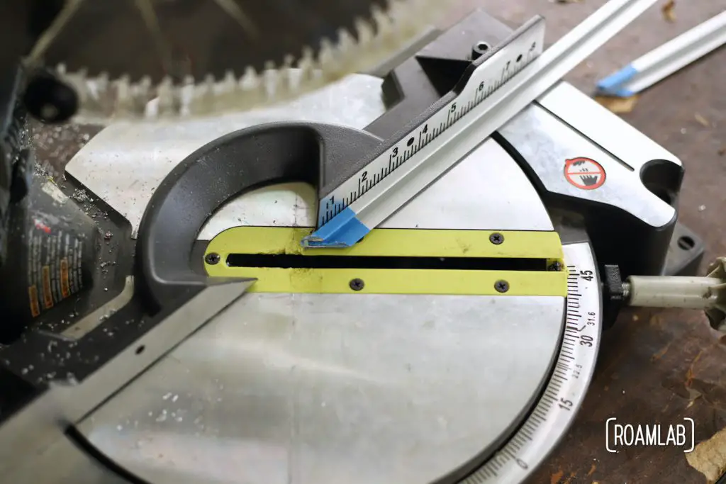 Aluminum rail on a miter saw set to cut the rail at 45-degrees.