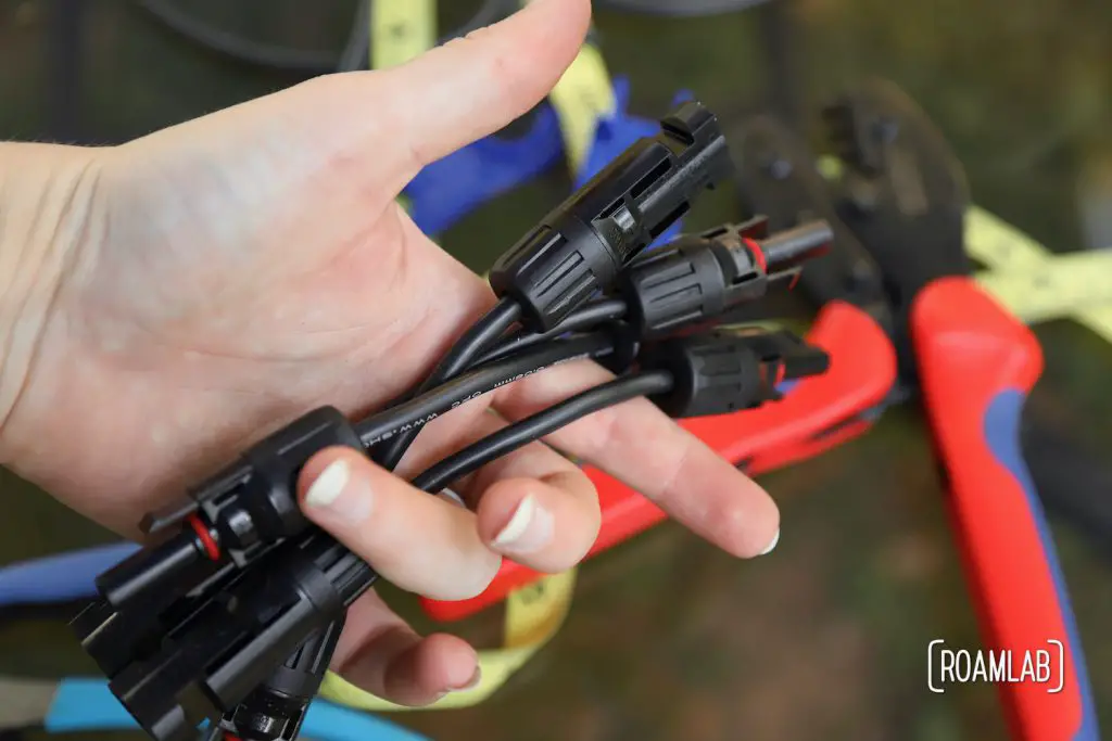 Hand holding short MC4 connectors for solar panels.