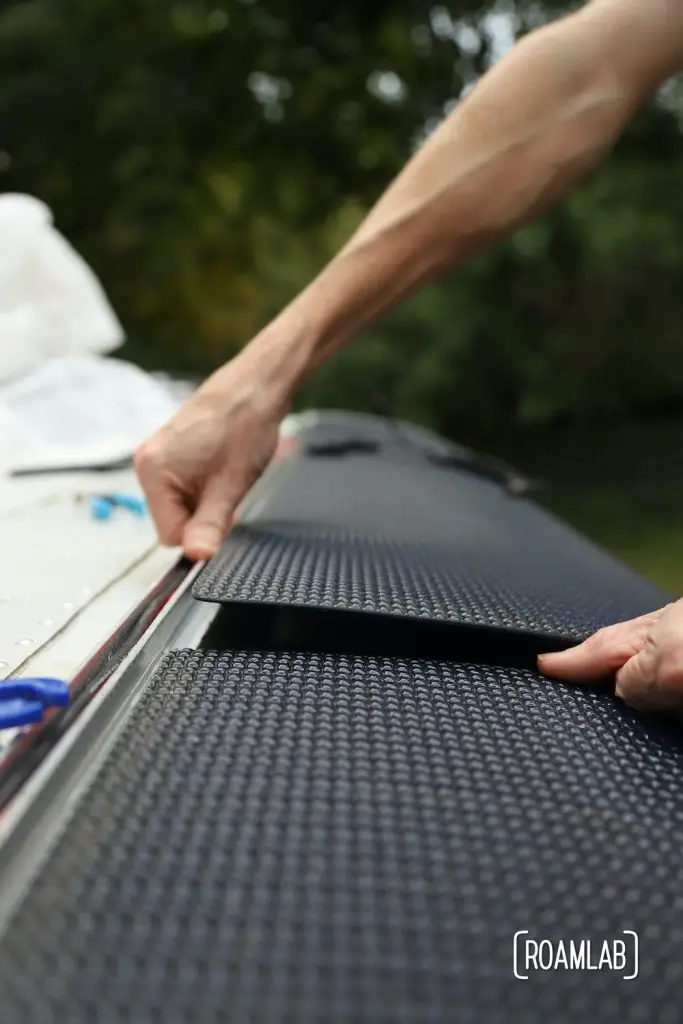 Carefully placing panels on truck camper roof and securing with velcro.