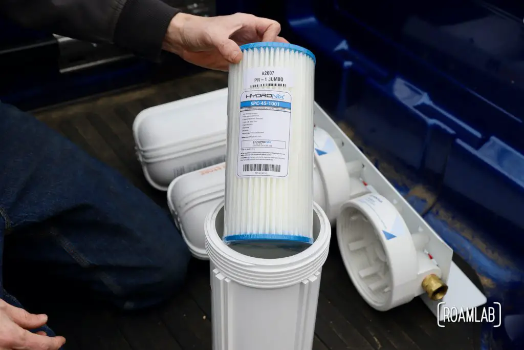 Hand holding a pleated polyester filter before placing it in the canister of a three part water filtration system.