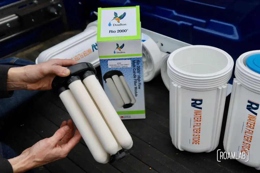 Hand holding a Doulton RIO 2000 water filter with packaging in the background and a canister nearby.