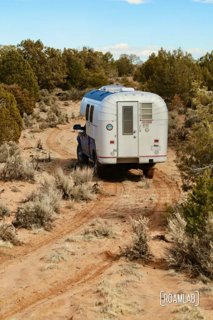1970 Avion C11 truck camper driving up a loose pink sand trail on the way to White Pocket in the Vermillion Hills of Arizona.