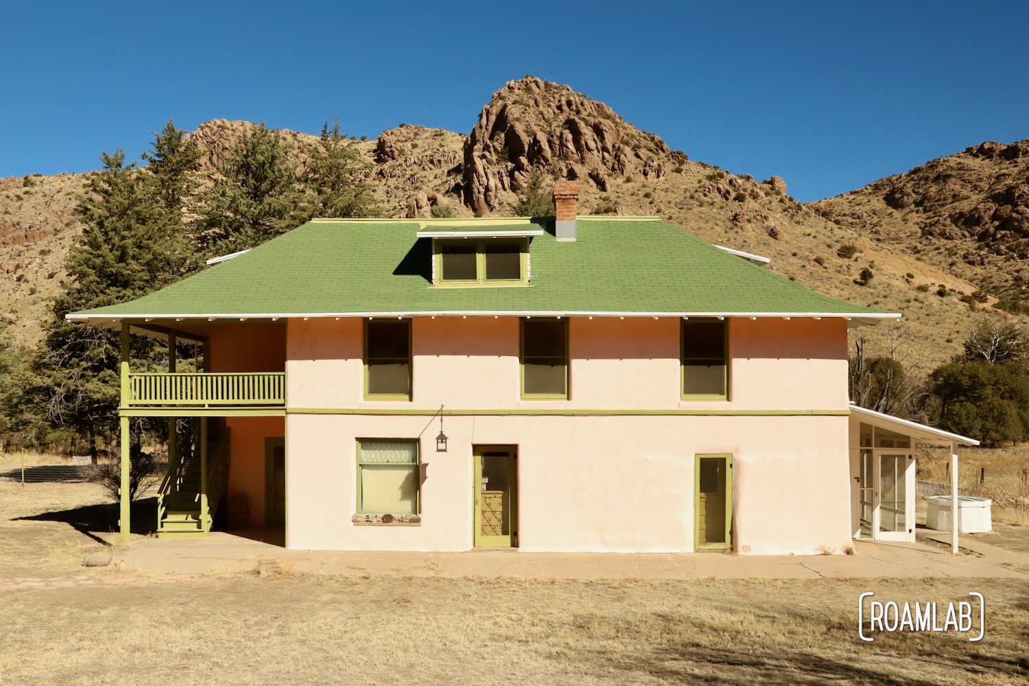 Pink and green two story home known as Faraway Ranch House with a rocky ridge in the background along Silver Spur Meadow Trail in Chiricahua National Monument Arizona.