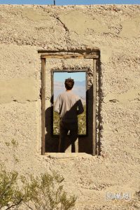 Man framed in the windows of an old stucco building.