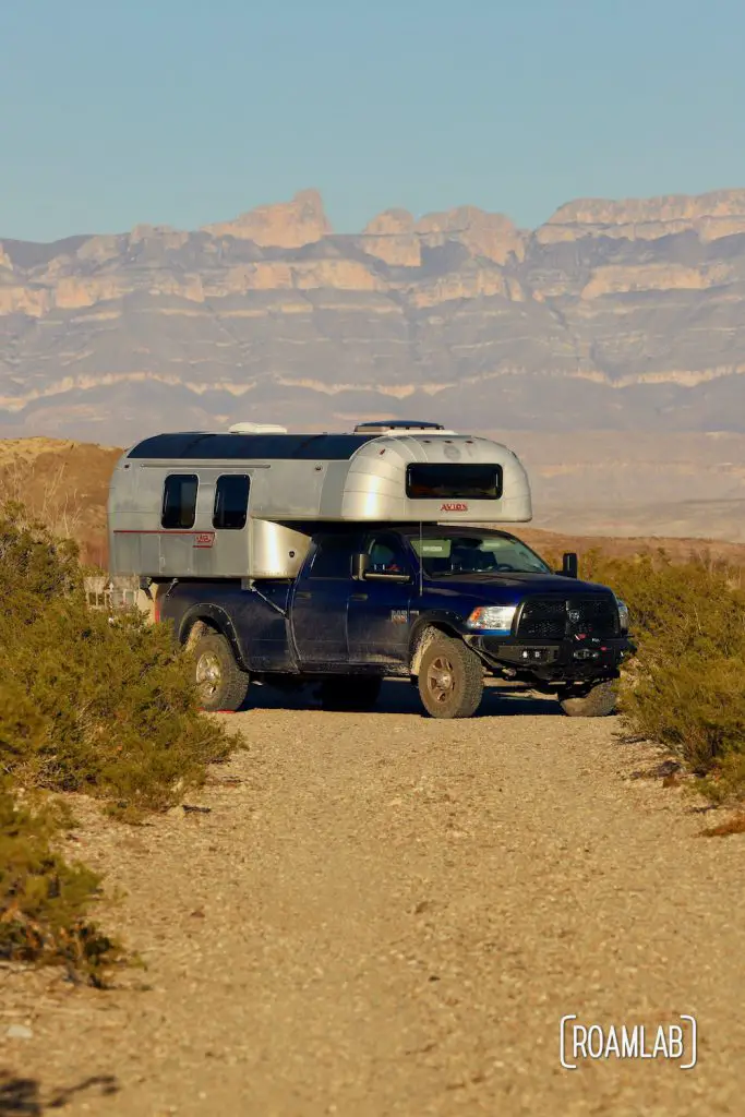Aluminum 1970 Avion C11 truck camper parked at the end of a dirt road with mountains in the background at Fresno Campsite off River Road in Big Bend National Park, Texas.