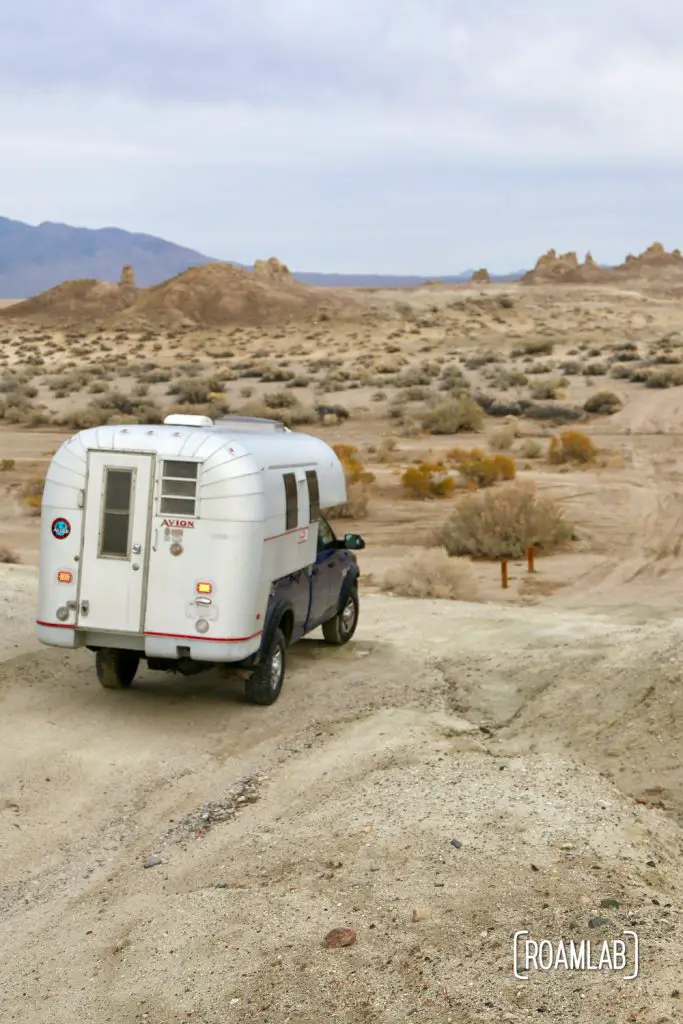 Aluminum 1970 Avion C11 truck camper driving down a dirt road in Trona Pinnacles Wilderness in south east California.