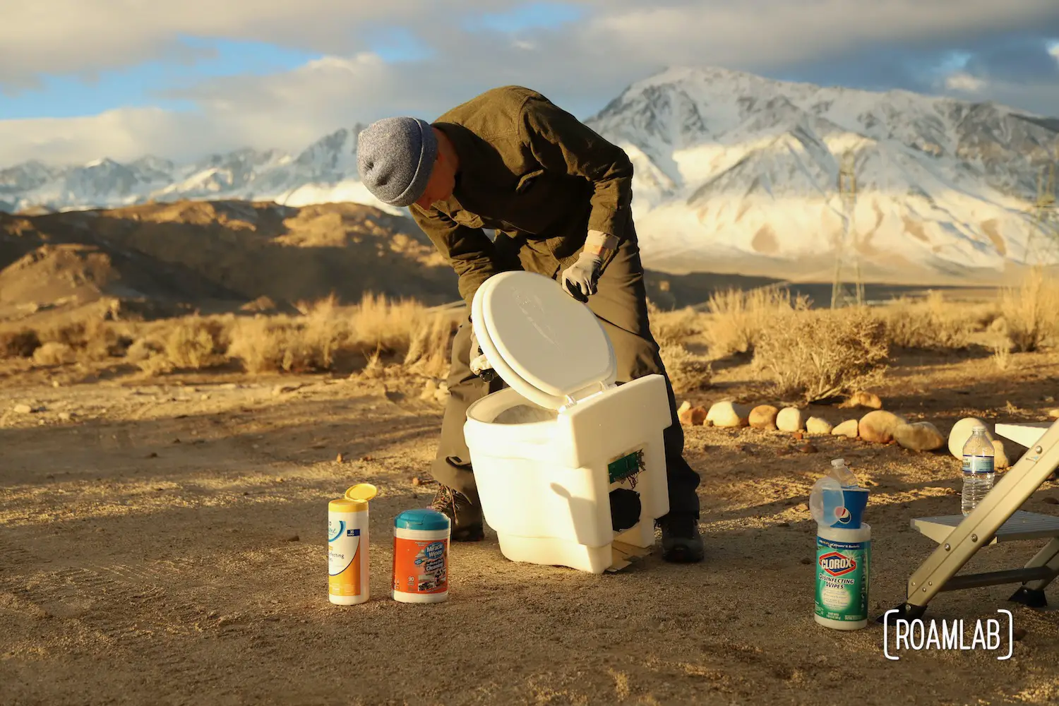 Man cleaning a dry flush toilet with the Sierra Nevada in the background.