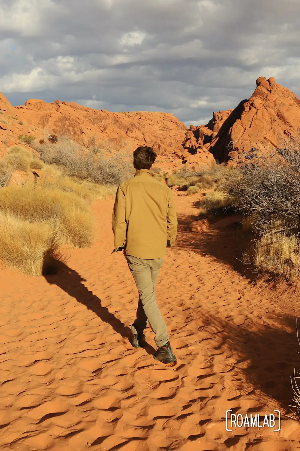 Man walking through the red sand on Mouse Tank Trail of Valley of Fire State Park