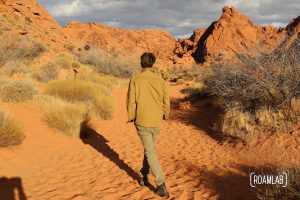 Man walking through the red sand on Mouse Tank Trail of Valley of Fire State Park