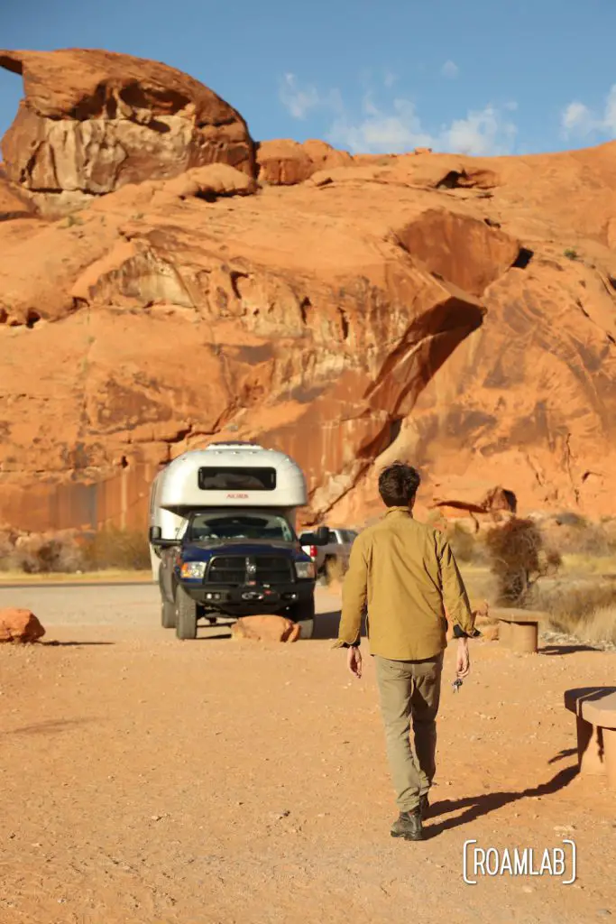 Man walking towards a 1970 Avion C11 truck camper at the Mouse Tank Trail head parking lot.