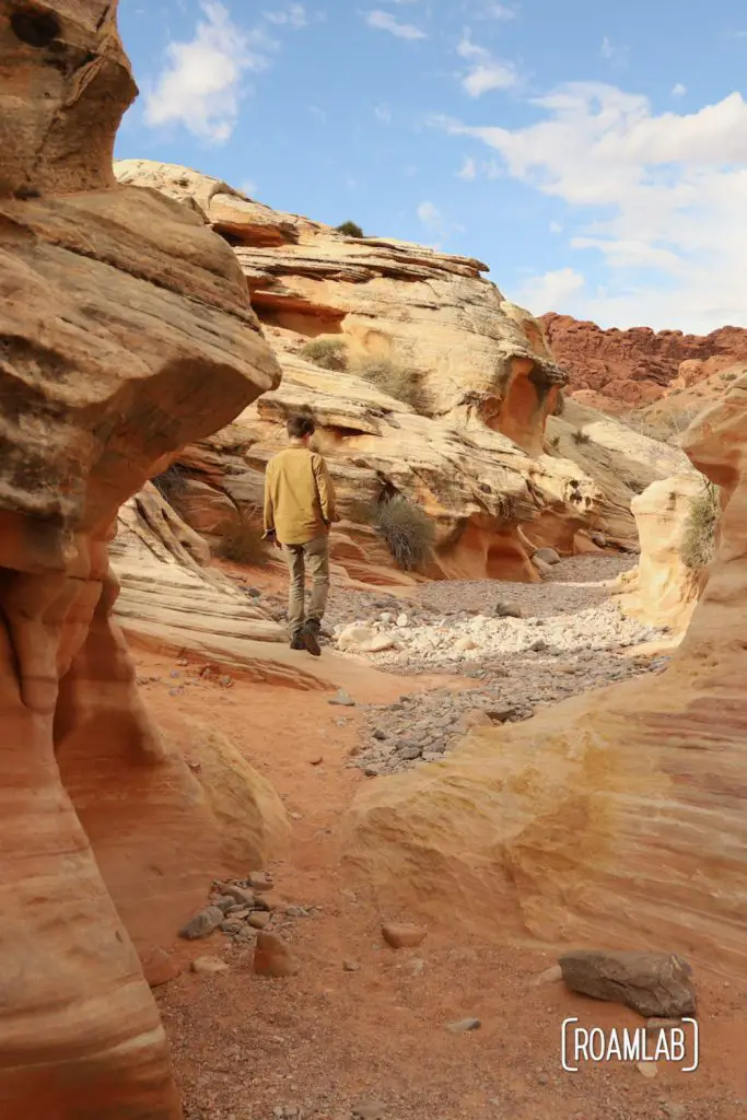 Man wandering through a red sandstone wash in White Domes Trail in Nevada's Valley of Fire State Park.