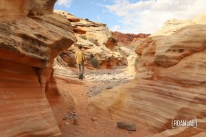 Man wandering through a red sandstone wash in White Domes Trail in Nevada's Valley of Fire State Park.