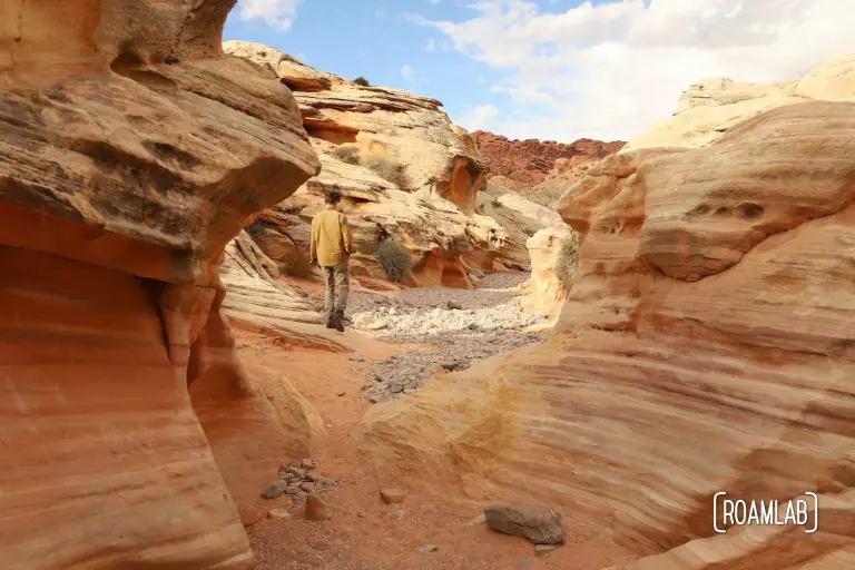 Man wandering through a red sandstone wash in White Domes Trail in Nevada's Valley of Fire State Park.