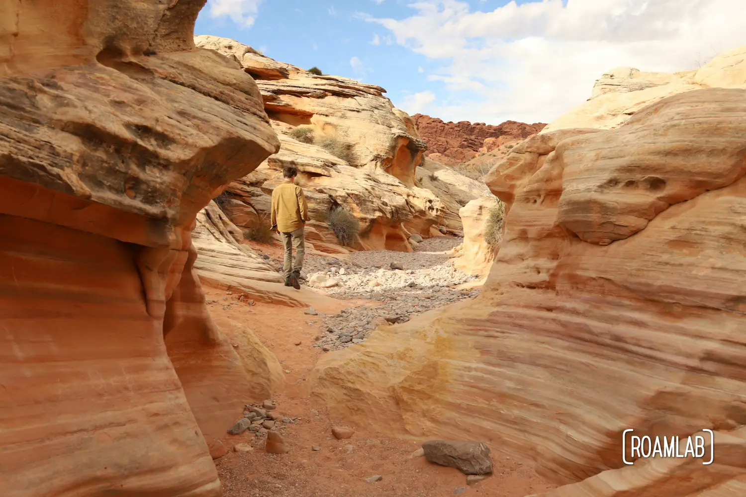 Man wandering through a red sandstone wash in White Domes Trail in Nevada's Valley of Fire State Park.