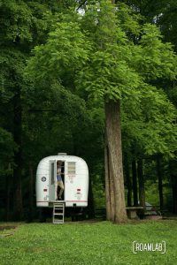 Man stepping out of a 1970 Avion C11 truck camper at Houchin Ferry Campground in Mammoth Cave National Park.