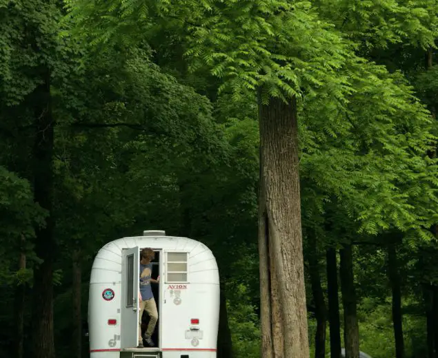 Man stepping out of a 1970 Avion C11 truck camper at Houchin Ferry Campground in Mammoth Cave National Park.