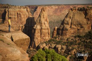 Man standing on a cliff side looking out over Colorado National Monument.