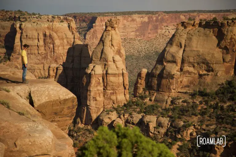 Man standing on a cliff side looking out over Colorado National Monument.