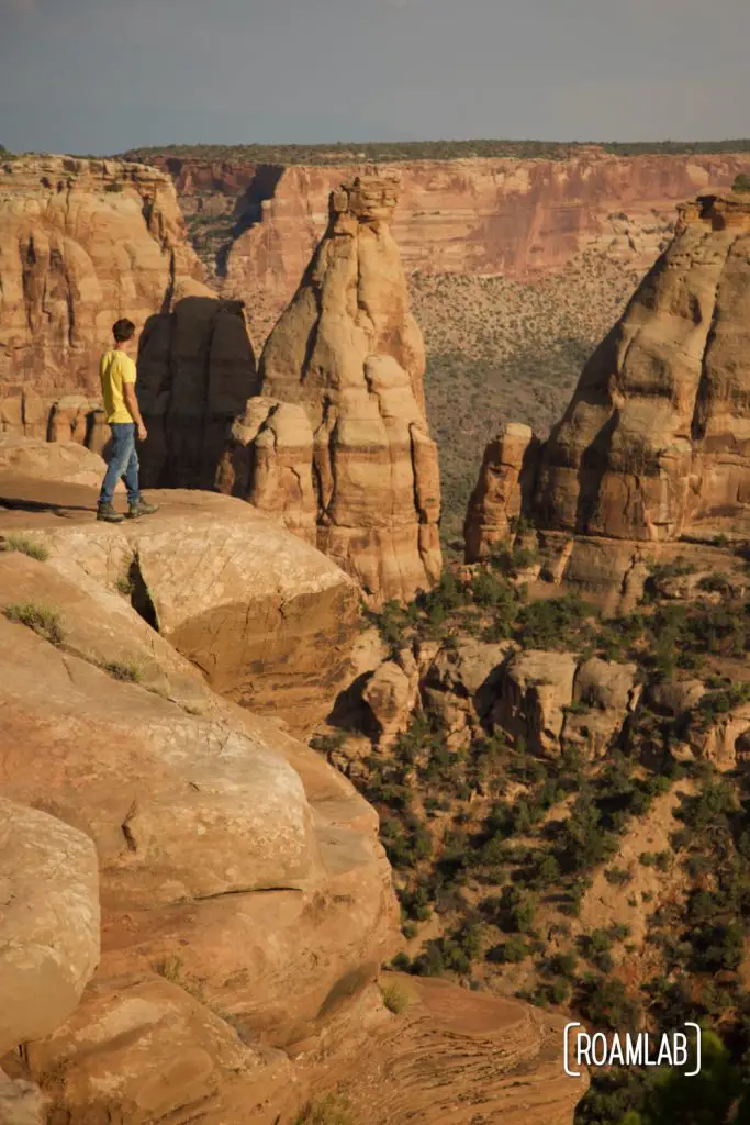 Man standing on a cliff side looking out over Colorado National Monument.