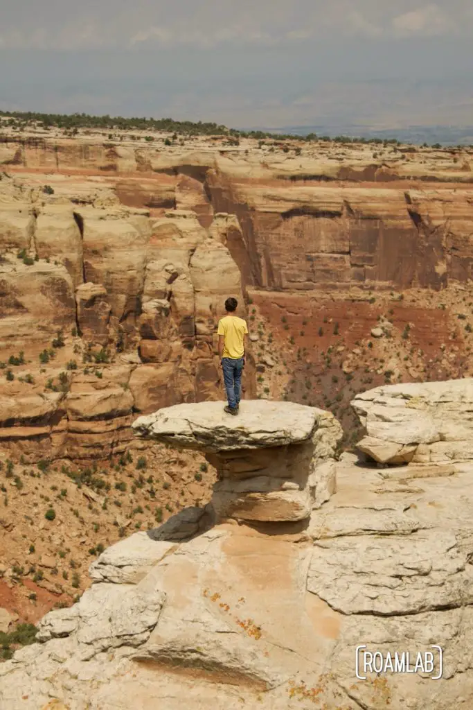 Man standing on a rock formation at Cold Shivers Point Overlook in Colorado National Monument.