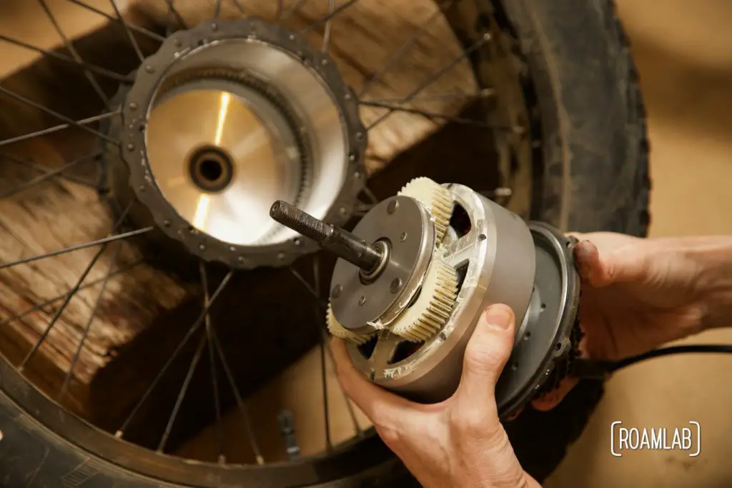 Hands holding an ebike motor just removed from the wheel.