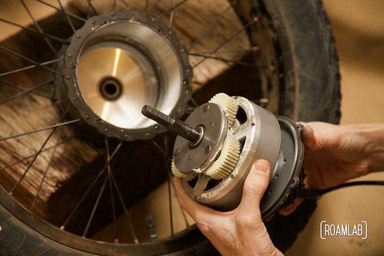 Hands holding an ebike motor just removed from the wheel.