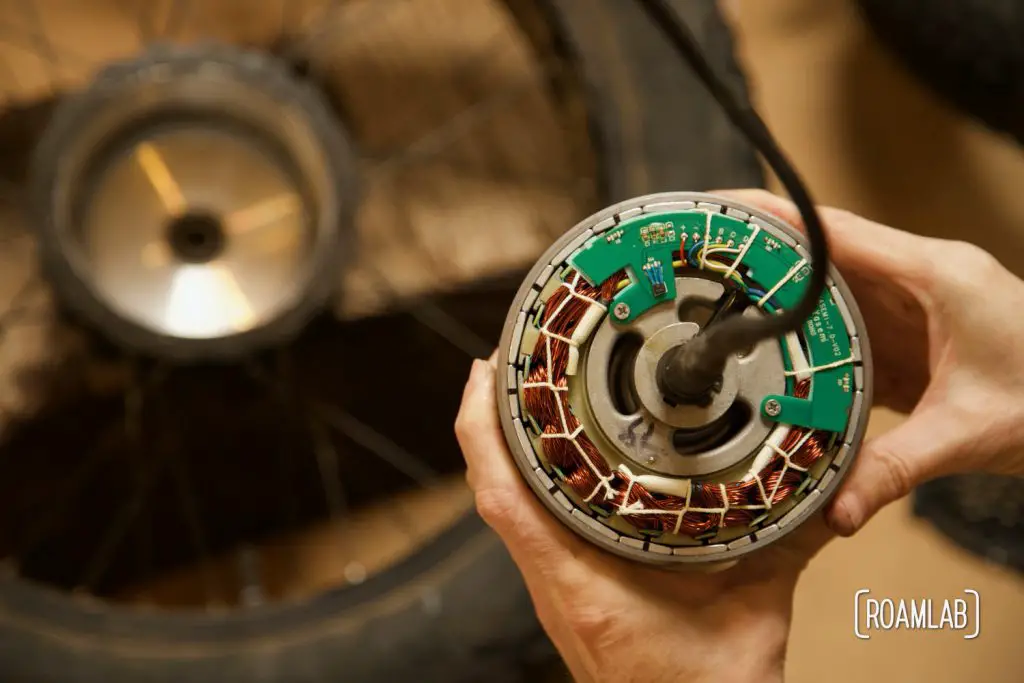 Hands holding an ebike motor with closeup view of circuitry.
