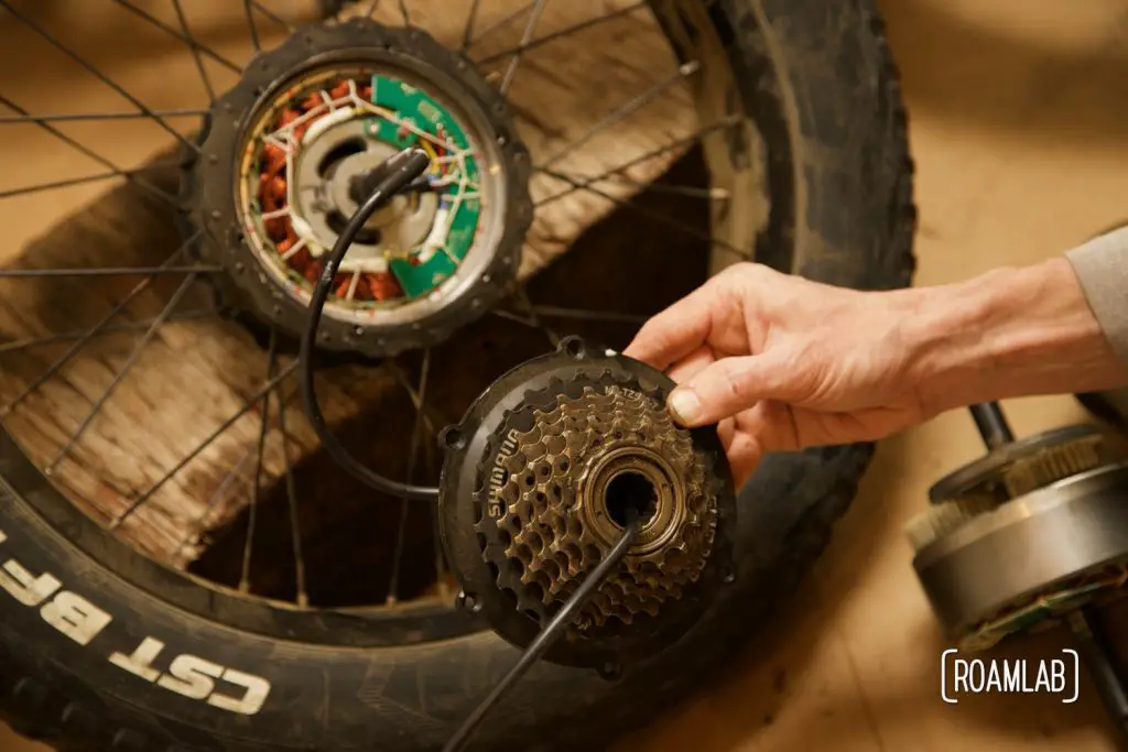 Hand holding a sprocket up to ebike wheel hub.