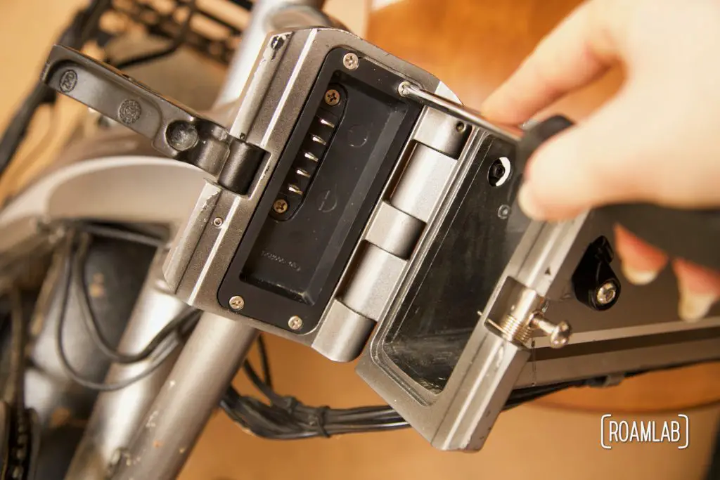 Hand unscrewing access panel to the wiring in the ebike frame.